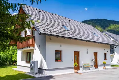 a white house with a bench in front of it at Apartments Zlati Rog in Kranjska Gora