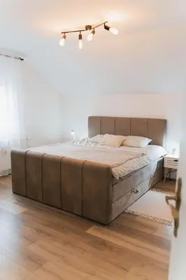 a large bed in a white bedroom with wooden floors at Vista Apartment in Sveta Trojica v Slovenskih Goricah
