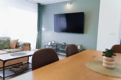 a living room with a table and a television on the wall at Vista Apartment in Sveta Trojica v Slovenskih Goricah