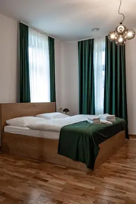 a bedroom with a bed with green curtains and a chandelier at Gostišče Pod Kostanji in Dobrna