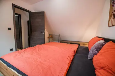 a bedroom with a bed with orange sheets and a mirror at Holiday Home Villa Rio in Terme Čatež in Čatež ob Savi