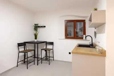 a kitchen with a sink and a table with stools at Apartments Napoleon in Ljubljana
