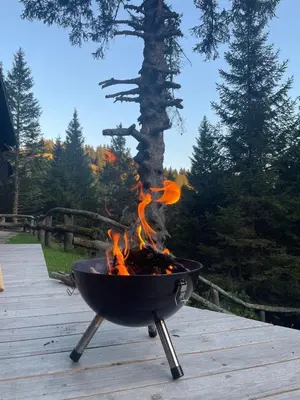 a grill on a deck with fire in it at New cosy apartment in nature - Krvavec in Cerklje na Gorenjskem