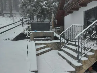 a snow covered porch with a bench and stairs at Apartma Escales -naselje Nune-Rogla in Zreče