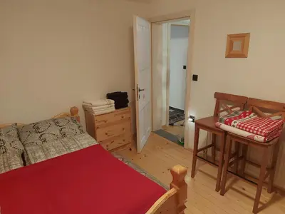 a bedroom with a bed and a table and a door at Apartma Escales -naselje Nune-Rogla in Zreče