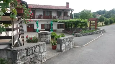 a house with a stone wall next to a street at Homestead Vrbin in Divača