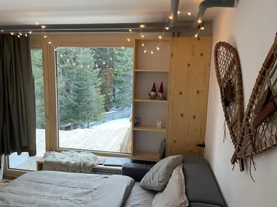 a bedroom with a bed and a large window at New cosy apartment, smučišče Krvavec in Cerklje na Gorenjskem