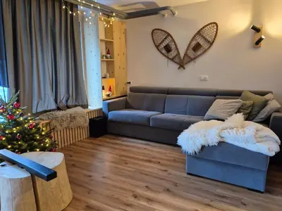 a living room with a couch and a christmas tree at New cosy apartment, smučišče Krvavec in Cerklje na Gorenjskem