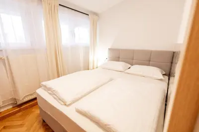 a bedroom with a bed with white sheets and a window at Hozi House -4 cozy apartment's in Ljubljana