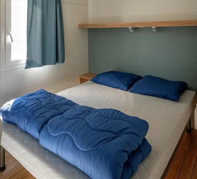 a bed with blue pillows on it in a bedroom at Eurocamp Mobile Homes Terme Catez in Brežice
