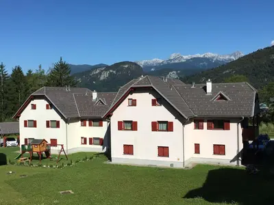 a large white house with a black roof at Apartment Happy Place in Bohinj