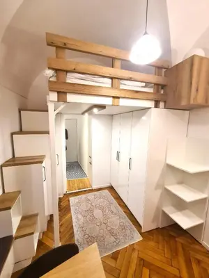 a loft apartment with white cabinets and a ladder at Courtyard Studio City Center in Ljubljana