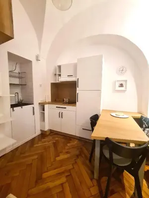 a kitchen with white cabinets and a wooden table at Courtyard Studio City Center in Ljubljana