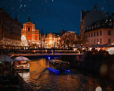 two boats on a river in a city at night at Courtyard Studio City Center in Ljubljana