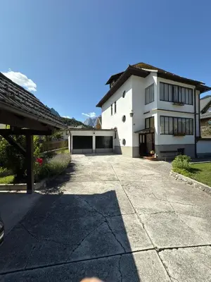 a large white house with a large driveway at Apartma Prisojnik in Kranjska Gora