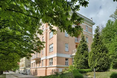a large brick building with trees in front of it at SLOAPART Apartments in Rogaška Slatina