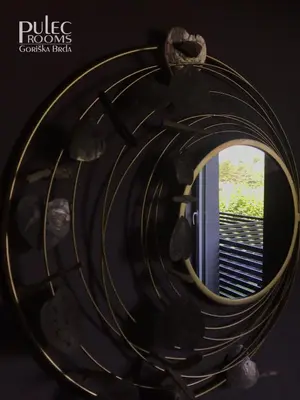 a round mirror in a room with a window at Apartma Sobe Pulec in Dobrovo