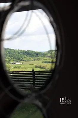 a view of a field through a round window at Apartma Sobe Pulec in Dobrovo