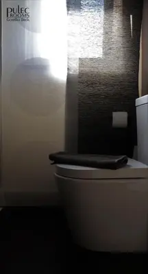 a white toilet in a bathroom with a window at Apartma Sobe Pulec in Dobrovo