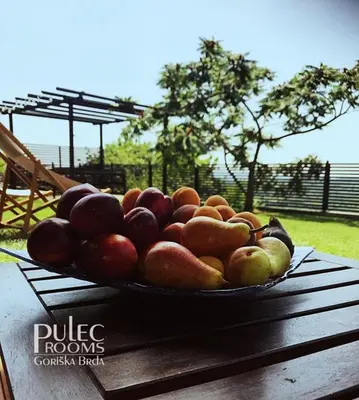 a plate of fruit on a wooden table at Apartma Sobe Pulec in Dobrovo