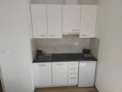 a white kitchen with white cabinets and a sink at Studio Apartma KIMI in Nova Gorica