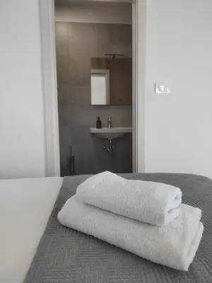 a bedroom with three towels on a bed with a sink at Studio Apartma KIMI in Nova Gorica