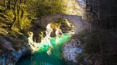 a bridge over a river with a waterfall at Apartma Mia Nadiža in Kobarid