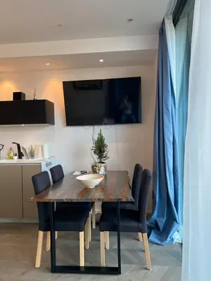 a dining room table with chairs and a television on the wall at Downtown appartment with a view in Ljubljana
