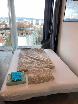 two beds in a room with a large window at Downtown appartment with a view in Ljubljana