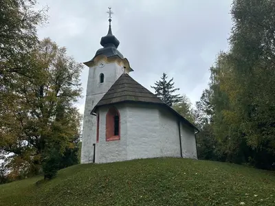 a small church on top of a grassy hill at Apartments Barbra - Robinson life in Slovenj Gradec