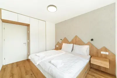a bedroom with a large white bed with a wooden headboard at Family apartments Soča Splash Home in Bovec