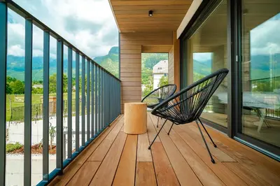 a chair on a balcony with a view of the mountains at Family apartments Soča Splash Home in Bovec