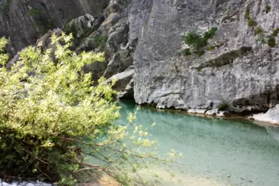 a body of water next to a rocky mountain at Apartment Pri Bricu in Kobarid