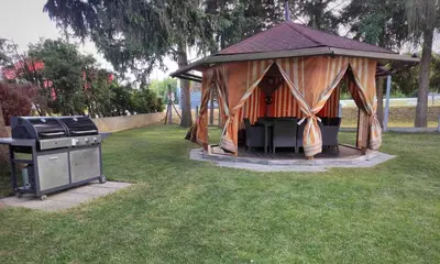 a gazebo with a grill in a yard at House IZI - parking, garden, 8 min ride to center in Maribor