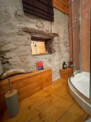 a bathroom with a stone wall and a tub and a window at Nadiza Hilltop Retreat in Breginj