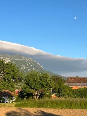 a cloud over a mountain with trees and houses at Apartment Rozalka Vipava valley in Podnanos