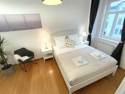 a bedroom with a white bed and a chair at Two-bedroom city apartment in Ljubljana