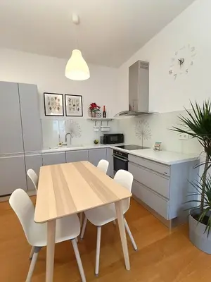 a kitchen with a wooden table and white cabinets at Two-bedroom city apartment in Ljubljana