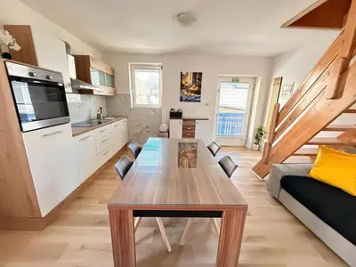 a living room with a wooden table and a kitchen at Apartments Rupnik in Bovec