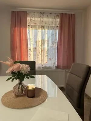 a table with a vase of flowers and a chair at Apartments Harmony Joe in Radenci