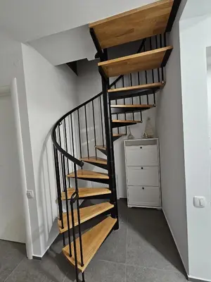 a wooden spiral staircase in a room with a dresser at Chalet Gozd Martuljek in Gozd Martuljek
