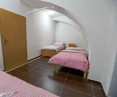 two beds with pink sheets in a room with an arch at Hostel - Rooms Kaj & Kaja in Slivnica pri Mariboru