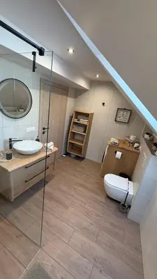 a bathroom with a sink and a toilet and a staircase at Slosarjeva Holiday House - Alpine View & Modern Comfort in Preddvor