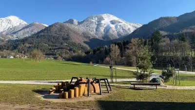a playground in a field with mountains in the background at Slosarjeva Holiday House - Alpine View & Modern Comfort in Preddvor
