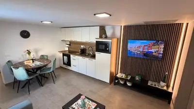 a kitchen with a table and a tv in a room at Slosarjeva Holiday House - Alpine View & Modern Comfort in Preddvor