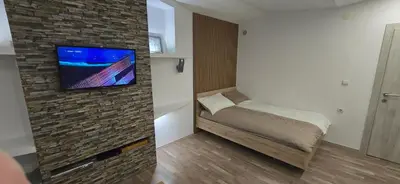 a small room with a bed and a tv on a brick wall at Apartma Minka in Miklavž pri Ormožu