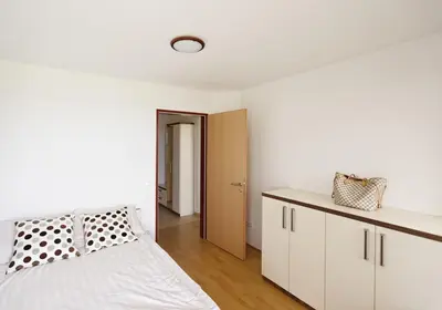 a bedroom with a white bed and a white cabinet at Apartma Moravske Toplice in Moravske Toplice