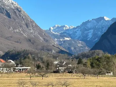 a village in a field with mountains in the background at Sunny AP22 in Bovec