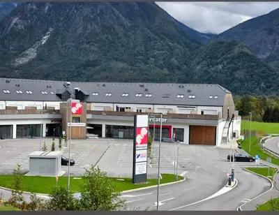 a large building with a parking lot in front of mountains at Sunny AP22 in Bovec