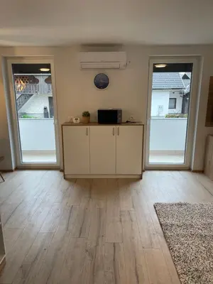 a living room with wooden floors and two large windows at Ten villages in Žirovnica